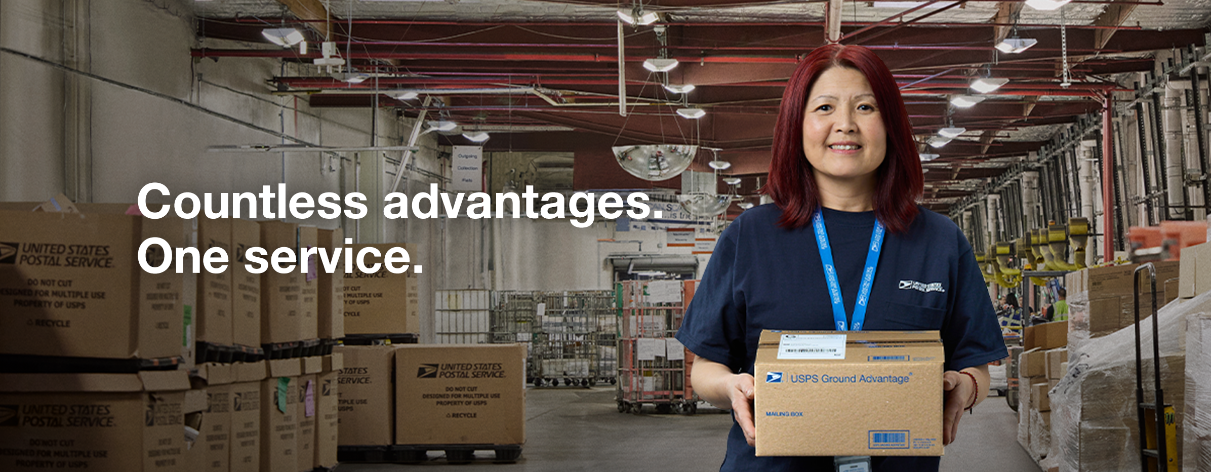 A female USPS worker carrying a brown package that has “USPS Ground Advantage®” printed on it.